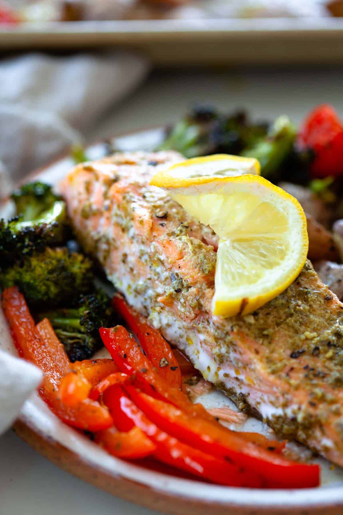 close up of sheet pan salmon and vegetables with a lemon slice on top